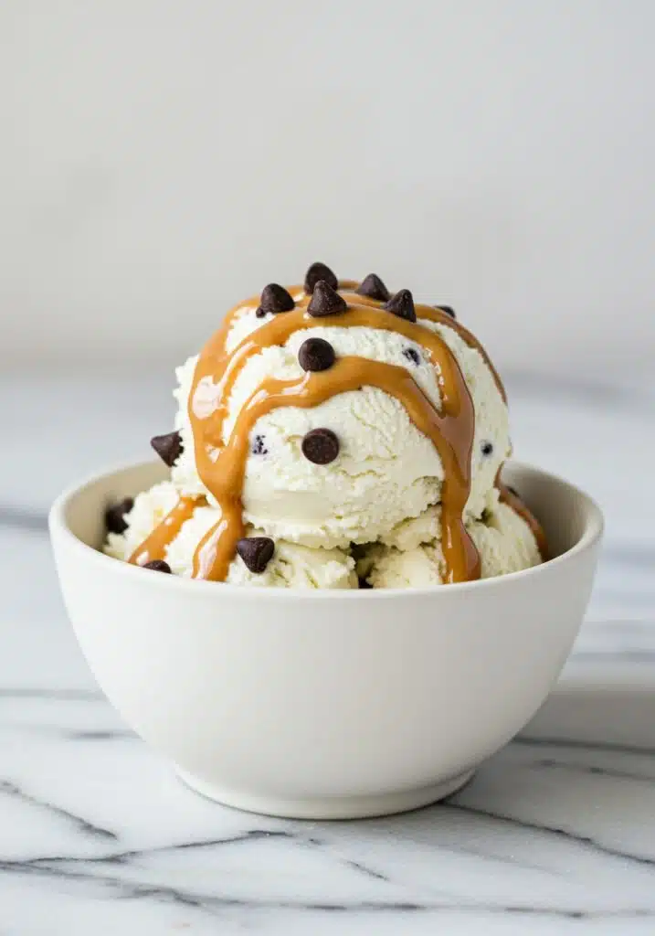 a white bowl of creamy cottage cheese ice cream topped with chocolate chips and a drizzle of peanut butter (3)