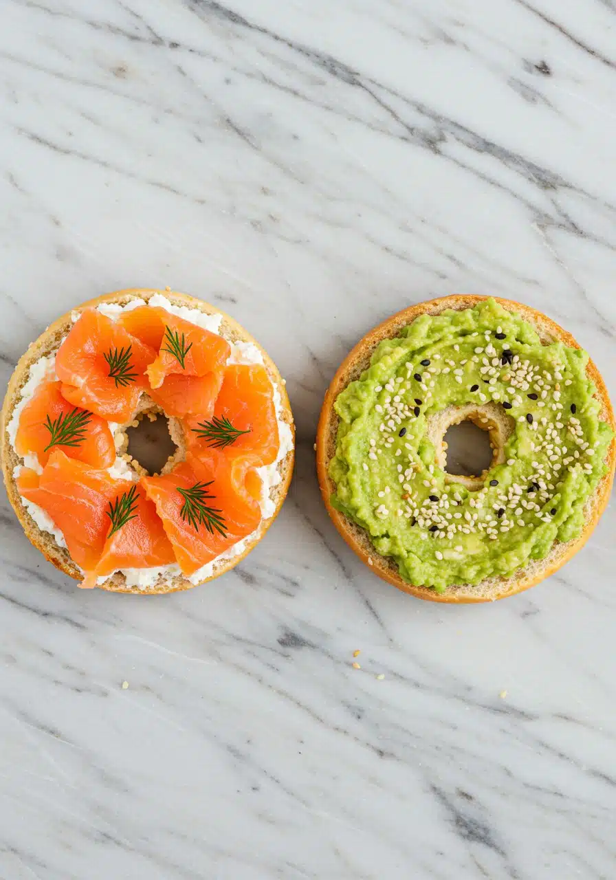 Two golden brown cottage cheese bagels sliced in half, one topped with smoked salmon, cream cheese, and dill
