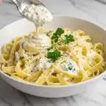 white bowl filled with creamy cottage cheese Alfredo sauce coating fettuccine pasta