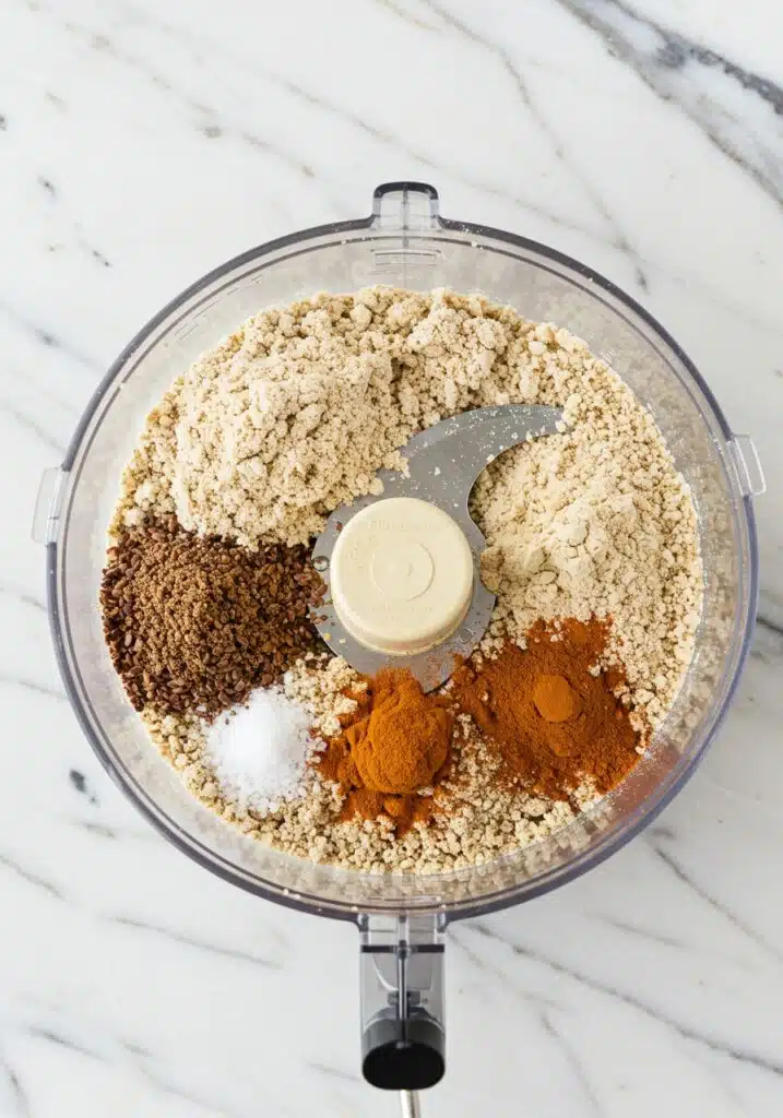 Dry ingredients for pumpkin protein balls inside a food processor before mixing.